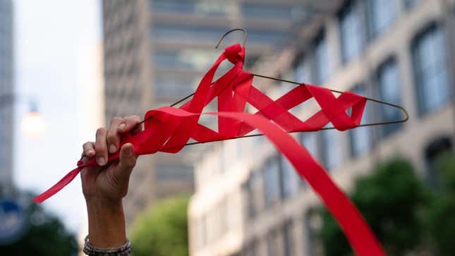 A woman holds up a coat hanger wrapped in red ribbon during a protest on June 25, 2022.