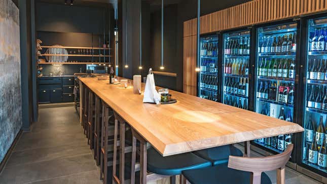 A long table stretches out before refridgerators filled with sake.