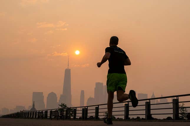The One World Trade Center and the New York skyline is seen in the background as a man jogs, while the smoke from Canada wildfires covers area on June 8, 2023 in New Jersey. 