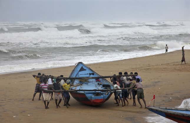 Fishermen move a fishing boat to a safer place along the shore ahead of cyclone Hudhud at Ganjam district in Odisha.