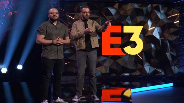 A photo of two men standing on a black-and-blue stage with a large E3 logo behind them.