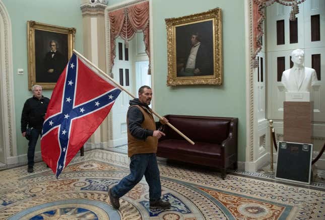 A supporter of President Donald Trump carries a Confederate flag during the insurrection of the US Capitol on January 6, 2021, in Washington, DC. - 