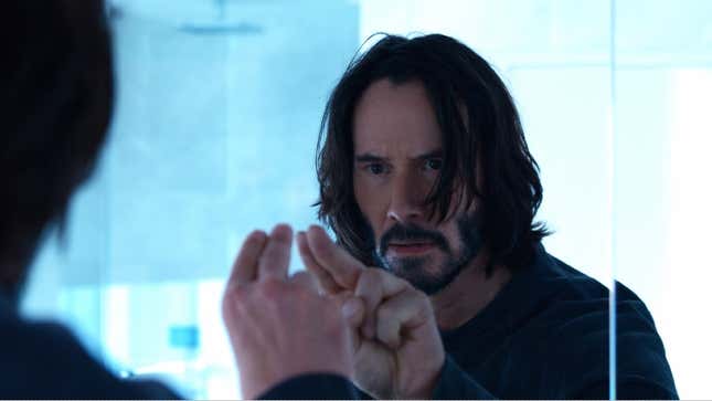 Keanu Reeves stares into a mirror in a scene from Matrix Resurrections.