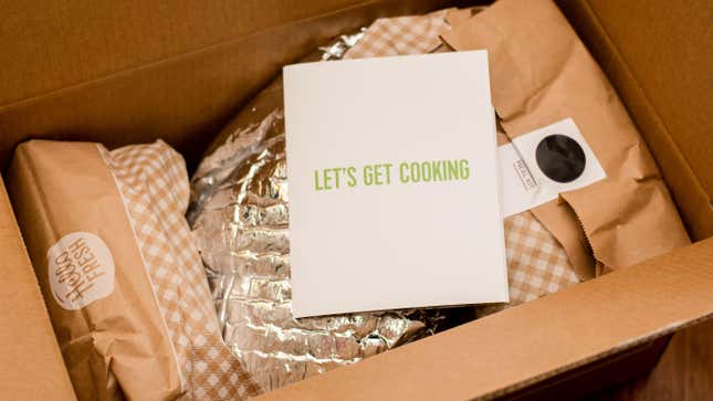 An open meal kit from Hello Fresh featuring various wrapped items in paper and foil packaging