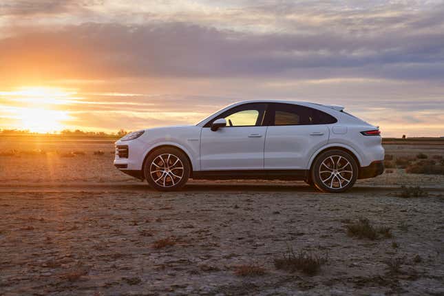 The 2024 Porsche Cayenne Coupe is parked in profile in the desert. It's white.