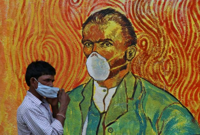 A man walks past a wall mural depicting Van Gogh's self-portrait but with a mask in Mumbai.