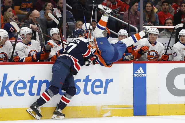 Apr 10, 2023; Washington, District of Columbia, USA; Washington Capitals left wing Beck Malenstyn (47) checks New York Islanders defenseman Adam Pelech (3) into the Islanders bench in the first period at Capital One Arena.