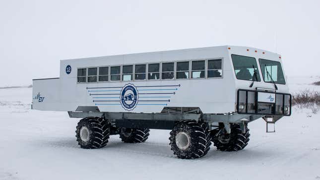 The electric tundra buggy out in the field on a snowy tundra.