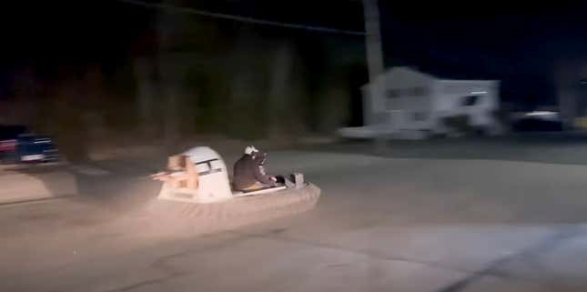 A man rides a personal hovercraft with jet engines on the back at night.