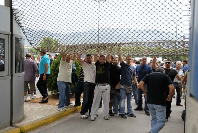 Protesters leave from the broken entrance of Greece’s Defense Ministry.