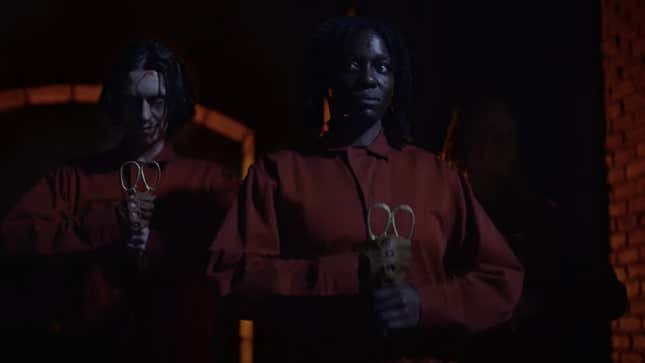 two evil teathered people in red jump suits holding scissors 