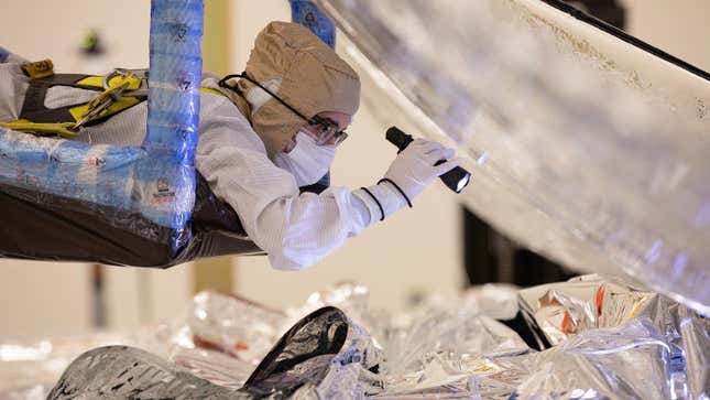 Archival image from February 2021, showing a Northrop Grumman technician inspecting the folding and packing of the Webb Space Telescope’s sunshield. 