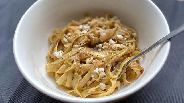 White bowl filled with cabbage pasta, topped with cheese crumbles