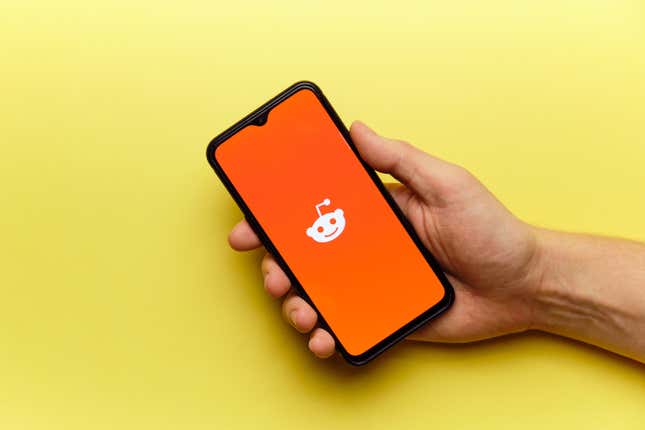 A phone with the Reddit logo on a yellow background.