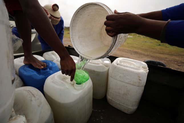 Residents fill up a containers with water from a polluted river.