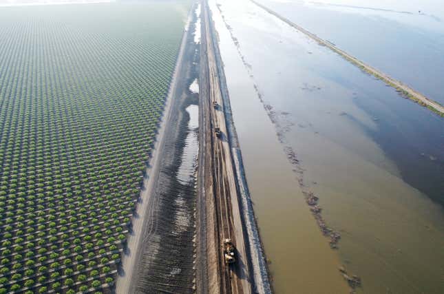 Workers work to reinforce and move a dirt levee near Corcoran, CA as floodwaters in Tulare Lake encroach on April 27, 2023. 