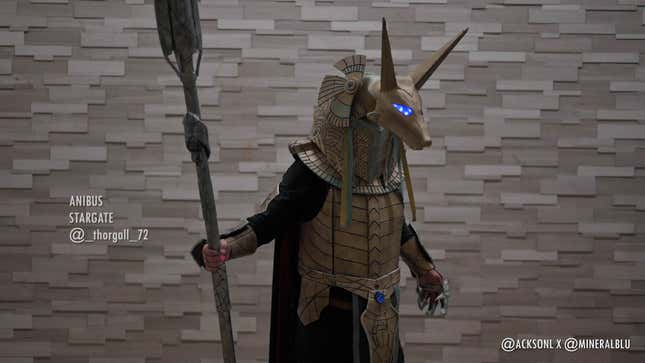 A cosplayer dressed as Anubis from Stargate stands with a staff. 