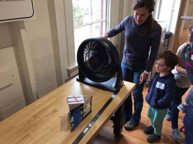 Four-year-old Martin Gadacz tests the wind-resistance of a building he designed on a computer and assembled with laser-cut cardboard at the new early-childhood fab lab. His mother, Florencia Falconi, starts the fan.