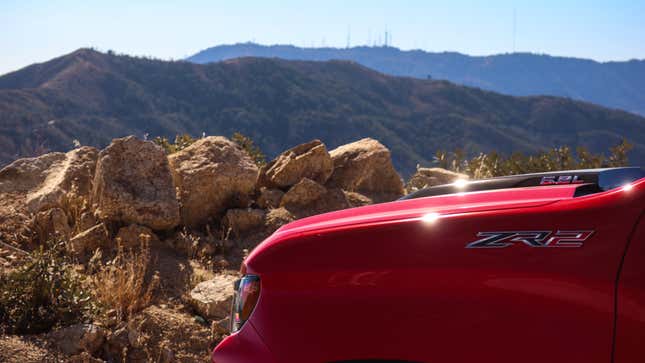 detail photo of the left front fender of a red 2023 chevy silverado zr2, with mountains in the background. the zr2 badge on the fender is visible in the foreground