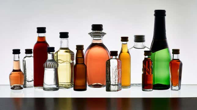 Many different sizes and shapes of liqueur bottles on white background