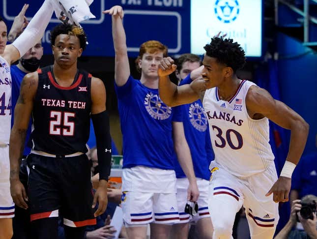 KU’s Ochai Agbaji celebrates as Texas Tech’s Adonis Arms looks on in yesterday’s double-OT thriller.