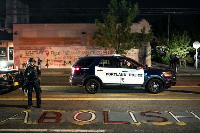 A Portland police officer looks down at graffiti calling for the abolition of cops after the crowd set fire to the Portland Police Association (PPA) building early in the morning on August 29, 2020, in Portland, Oregon. 