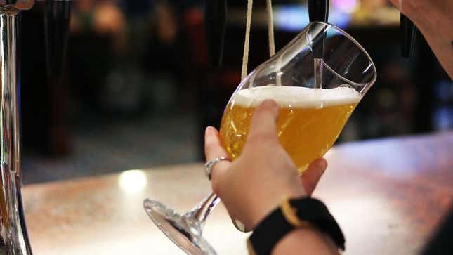 Bartender's hands holding pint of beer as tap pours