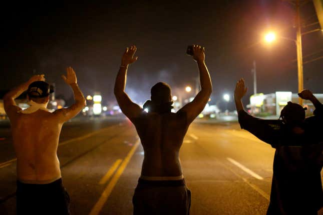 FERGUSON, MO - AUGUST 17: Demonstrators raise their arms and chant, “Hands up, Don’t Shoot”, as police clear them from the street as they protest the shooting death of Michael Brown on August 17, 2014 in Ferguson, Missouri.