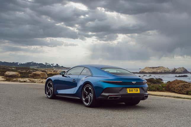 Rear three-quarter view of blue Bentley Batur under gray clouds