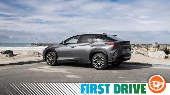 A dark gray 2023 Lexus RZ 450e suv is parked in front of a beach.