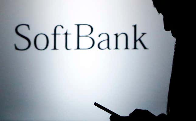A pedestrian holding a mobilephone walks past a logo of SoftBank Corp in front of its branch in Tokyo December 31, 2013. Japan’s SoftBank Corp is in talks to acquire U.S. wireless carrier T-Mobile US Inc and is discussing funding for a deal with financial institutions, sources close to the matter said last Wednesday. REUTERS/Yuya Shino (JAPAN – Tags: BUSINESS TELECOMS) – GM1E9CV1IRR01
