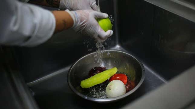 Person rinsing produce at sink