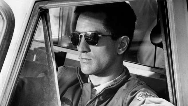 Robert DeNiro wearing sunglasses and sitting in a taxi on the set of Taxi Driver.