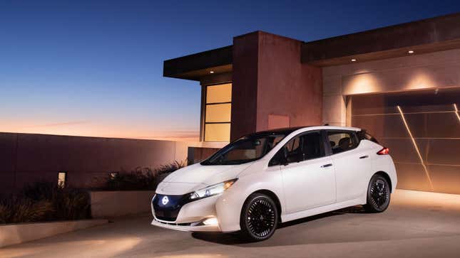 A photo of a Nissan Leaf EV parked outside a house at sunset. 