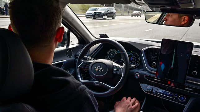 A man sat behind the wheel of a self-driving car. 