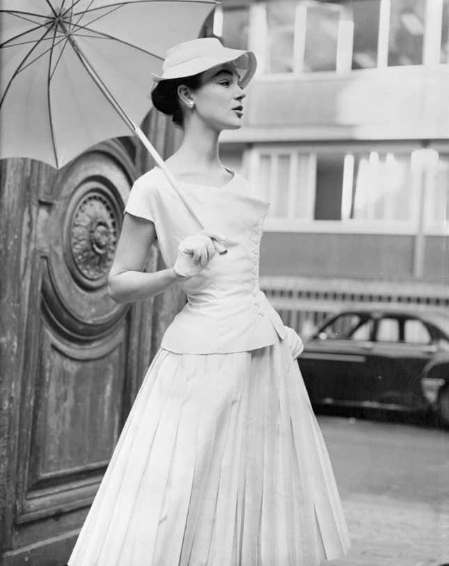 (Original Caption) Attention: Women's Page Editor. Paris, France: "Orlon" fiber adapted to silks and satins and the heavier weight of wool is being featured in the current spring-summer Paris fashion collections. Here are two fashions in the orlon fabric. At left, a Jean Desses two-piece dress in chalk white shantung or orlon-acrylic fiber and silk. This crisp yet supple fabric is lightweight and soft and its pleats are durable. At right: Jean Patou's new collection includes this new-length coat in white flannel of orlon-acrylic fiber and wool. It is soft to the touch, yet warm and lightweight. February 17, 1955.