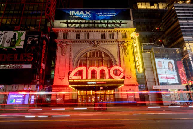 An AMC theater in a busy city with bright neon lights