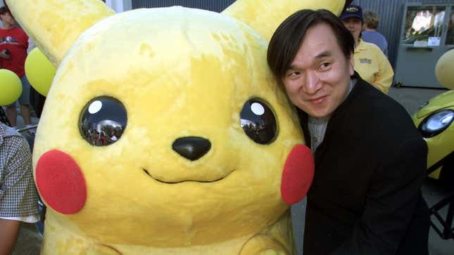 Pokémon Company president Tsunekazu Ishihara stands next to a person in a Pikachu costume. 