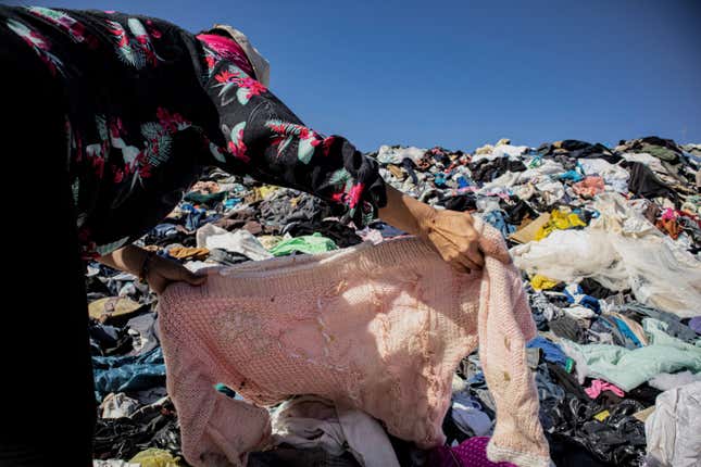 A person searches for clothing in a pile of discarded garments in the Atacama Desert.