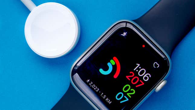An Apple Watch next to a wireless charger on a blue background