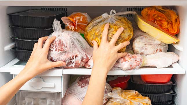 Person trying to stop food from falling out of freezer.