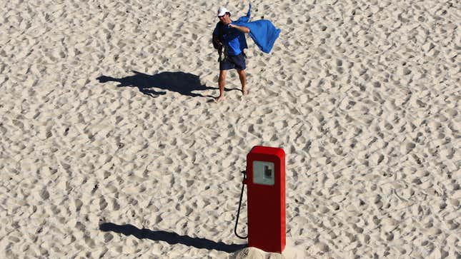 A photo of a gas pump on a beach. 