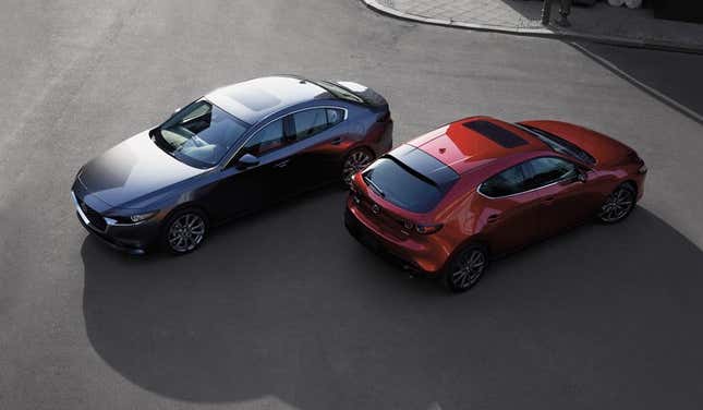 Two Mazda3s perch pristinely in a parking paddock.