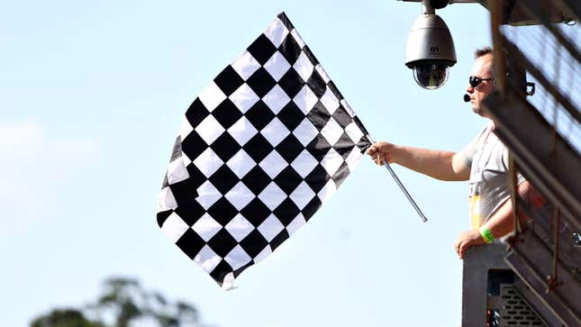 A marshal holds the black and white checkered flag to signal the end of the Brazilian Grand prix. 
