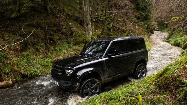 A photo of a black Land Rover Defender driving in a river.