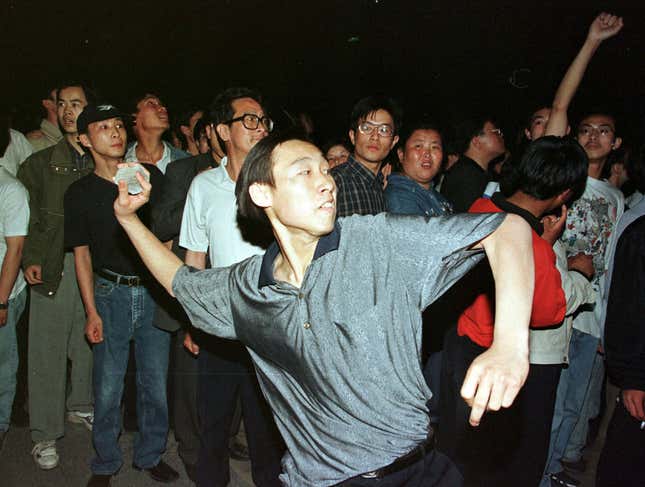 A student throws a rock during a protest outside of the US embassy in Beijing.
