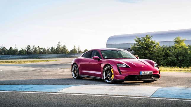 A photo of a raspberry colored Porsche sports car parked on a race track. 