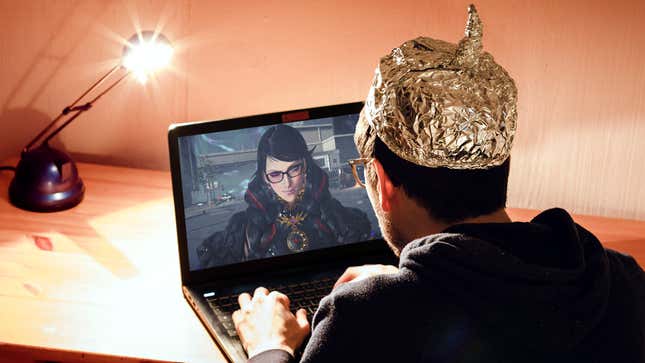 A man with a tinfoil hat sits alone in a room staring at his laptop which has an image of Bayonetta on his screen winking back at him. 