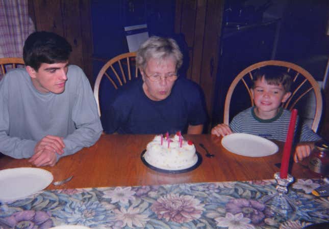 Adult Nickerson and young Nickerson sit next to their grandma, who blows out birthday candles.
