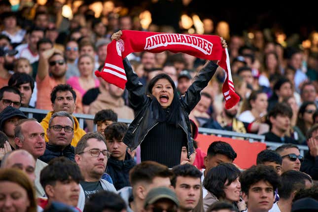 A fan holds an "Aniquiladores" soccer scarf at the Kings League final.